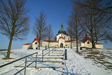 Winter scene with view of Pilgrimage Church of St John of Nepomuk at Zelena Hora on top of a hill at Zdar nad Sazavou during cold bright sunny day with clear blue sky, snow and steps up