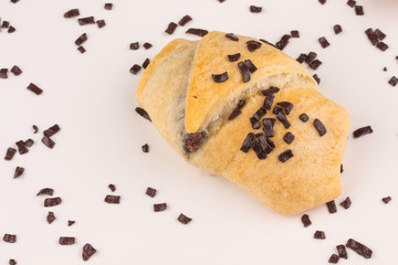 kleines Schokoladen Croissant mit Schokoladenstreuseln vor weißem Hintergrund