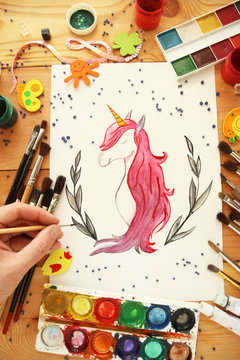 man draws unicorn. brushes and paints