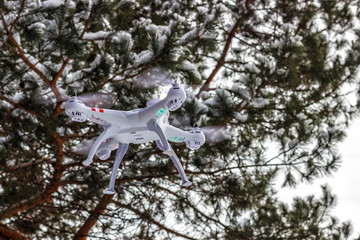 Flight of the drone in the winter forest. The concept of unmanned aircrafts Quadcopter, technology and surveillance.