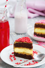 three colorful pieces of cake with sprinkles of sugar hearts on a wooden table