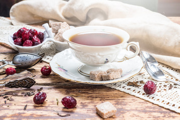 Fototapeta na wymiar Cup of tea, sugar cubes and dried berries on wooden table