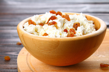 Homemade cottage cheese with almonds and raisins in a bowl on a wooden table.