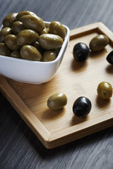 Olives in a white bowl on a dark wooden table