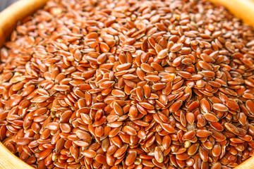 Many flax seeds are scattered in the background, and poured into a clay plate.