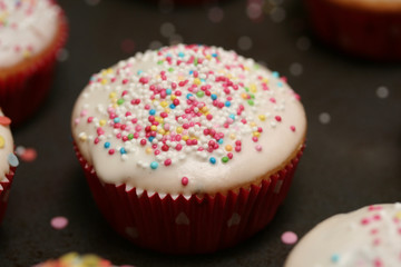 Muffins Cup Cakes mit weißem Zuckerguss und bunten Streuseln