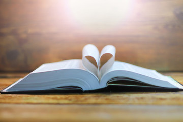 Open book on a wooden table. folded pages in the form of a symbol of the heart