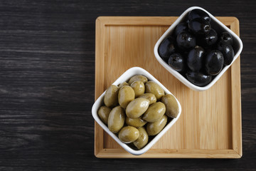 Olives in a white bowl on a dark wooden table