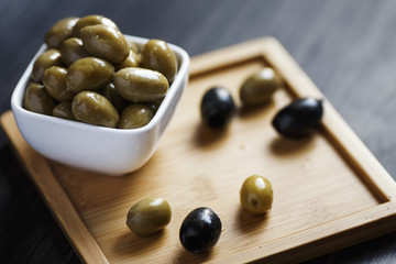 Olives in a white bowl on a dark wooden table