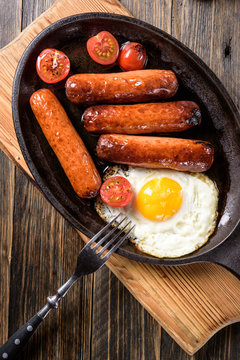 fried sausages with fried eggs in a frying pan