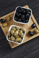 Olives in a white bowl on a dark wooden table