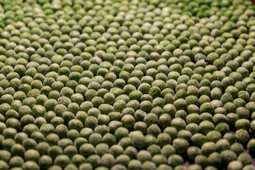 green deep frozen garden peas on brown wooden desk - above, close up