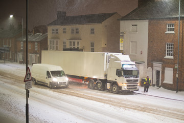 truck stuck in traffic in snow storm with buildings in background UK