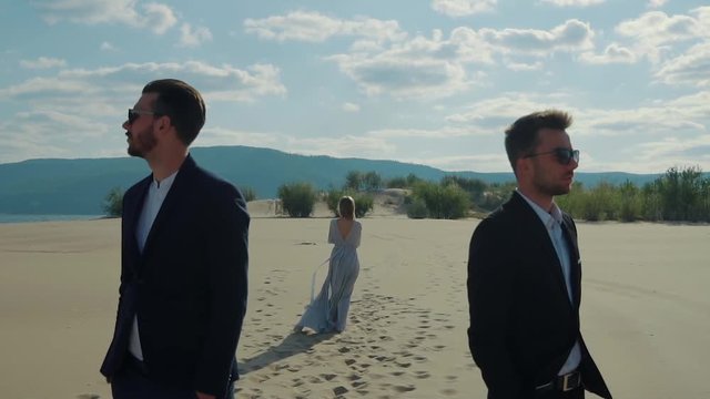 Blonde is abandoning her two boyfriends, leaving them in a desert. Dramatic story of love triangle, picturesque landscape of sandy beache