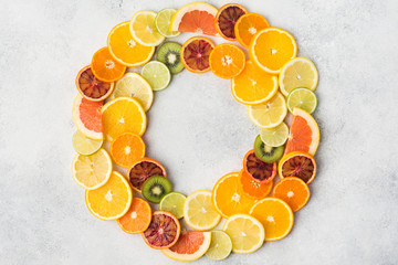 Different varieties of citrus fruits and kiwis arranged in a circle frame on white table, top view,...