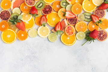 Colourful fruits background, oranges, clementines, blood oranges, kiwis, strawberries and grapefruits on white table background, top view, copy space for text, selective focus