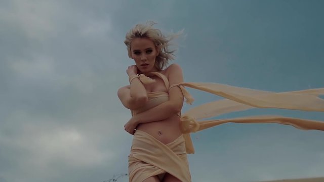 Lonely beautiful woman is looking like a fallen angel without wings. She is walking in a desert, touching her naked shoulders, looking in camera sensually