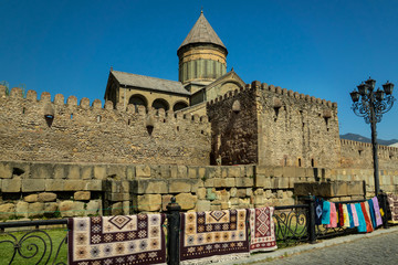 Fototapeta na wymiar Georgian Svetitskhoveli cathedral in Mtskheta city with typical craft and carpets ina foreground.