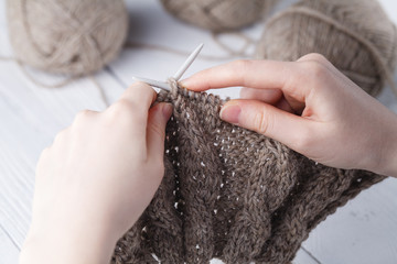 The woman knits woolen clothes. Knitting needles. Close-up. natural wool