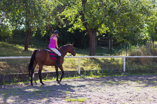 Woman is riding horse in paddock