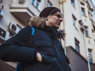 Fototapeta premium young fashion male tourist walking in the streets with backpack on cloudy day