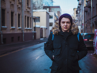 Obraz premium young fashion male tourist walking in the streets with backpack on cloudy day