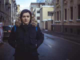 Obraz premium young fashion male tourist walking in the streets with backpack on cloudy day