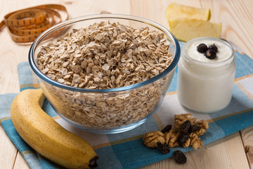 oat flakes, yogurt, bananas and nuts, the measuring tape lies next to, the concept of a healthy diet