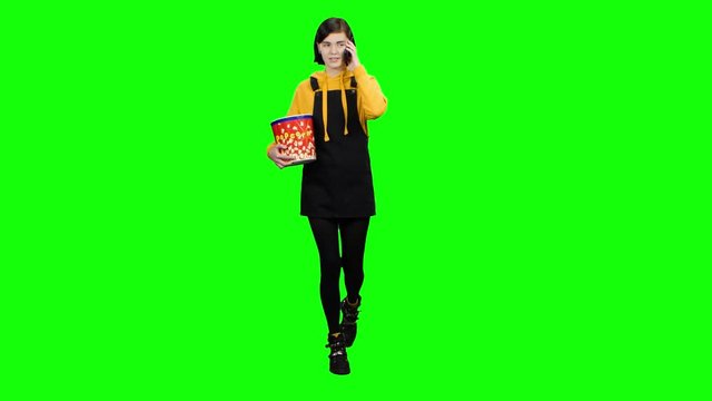 Teenager speaks on the phone with popcorn in his hands. Green screen