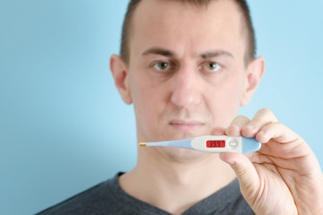 Man with a thermometer in his hand. High body temperature