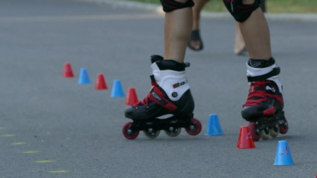 Young girl roller skating in the park. Close-up view of female legs in roller blades.