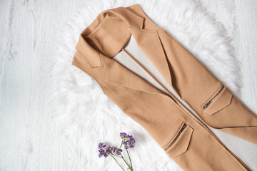 Brown jacket without sleeves on white fur. Close up. Fashionable concept
