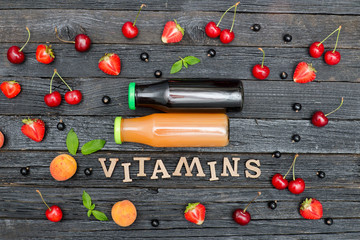 Two bottles of juice, the inscription Vitamins and fruits. Wooden background.