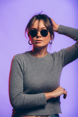 Happy young woman on a purple background with sunglasess