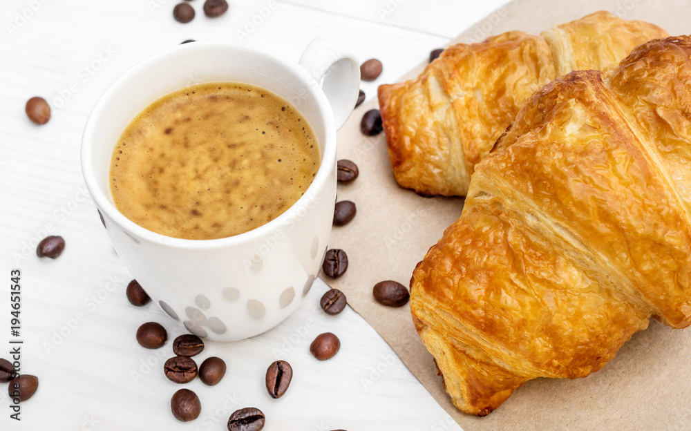 Wall mural cup of coffee, two croissants on napkin and coffee beans on the table. top view.