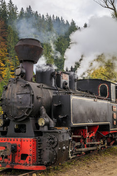 Old steam locomotive passing by trees against sky