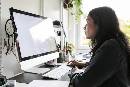 Side view of female design professional using computer while sitting in home office