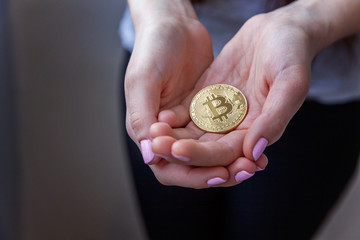 Cryptocurrency golden bitcoin coin in woman hand. Electronic virtual money for web banking and...