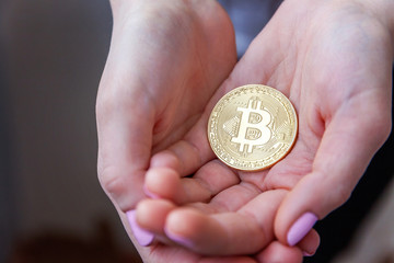 Cryptocurrency golden bitcoin coin in woman hand. Electronic virtual money for web banking and international network payment. Symbol of crypto currency