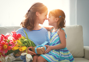 happy mother's day! child daughter   gives mother a bouquet of flowers to tulips and gift