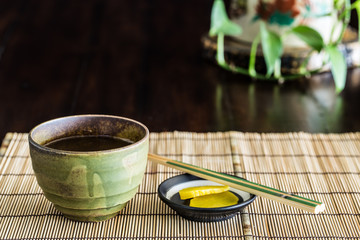 Green tea cup and Chopstick on bamboo mat.