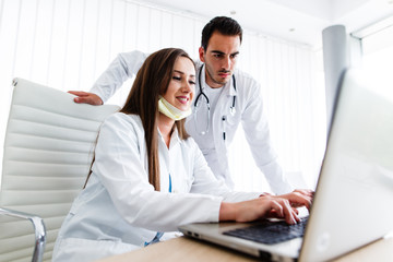 Beautiful nurse and young doctor works on laptop