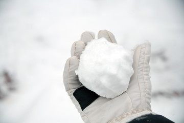 real snowballs with their hands clasped from the fresh snow in winter on the street