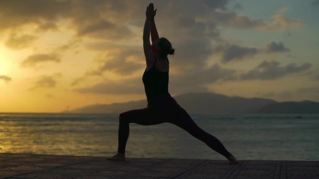 Silhouette girl do warrior namaste yoga pose at sunset beach rapid slow motion