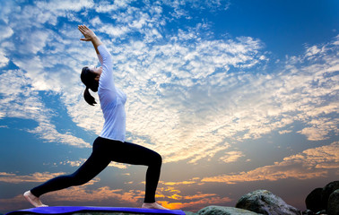 Sporty young woman doing yoga practice with sky background - concept of healthy life and natural balance between body and mental development