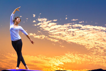 Sporty young woman doing yoga practice with sky background - concept of healthy life and natural balance between body and mental development