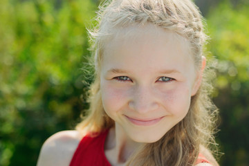 portrait of cute little blonde caucasian girl on green grass background