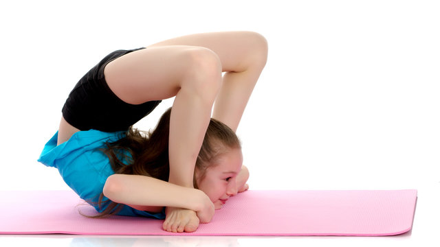 The little gymnast perform an acrobatic element on the floor.