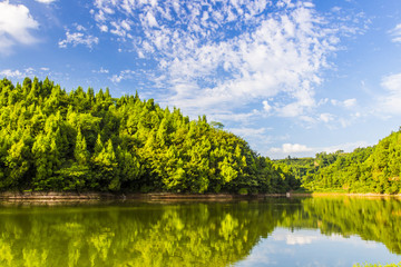 Calm lake and green hills in summer sunlight