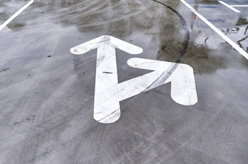 White arrow sign painted on the wet grey floor